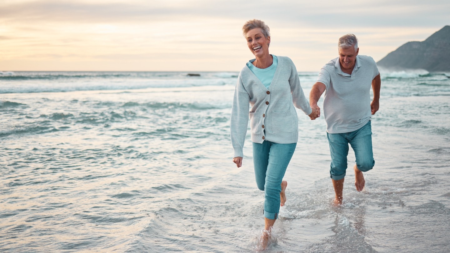 Retired couple enjoying a walk together along the beach